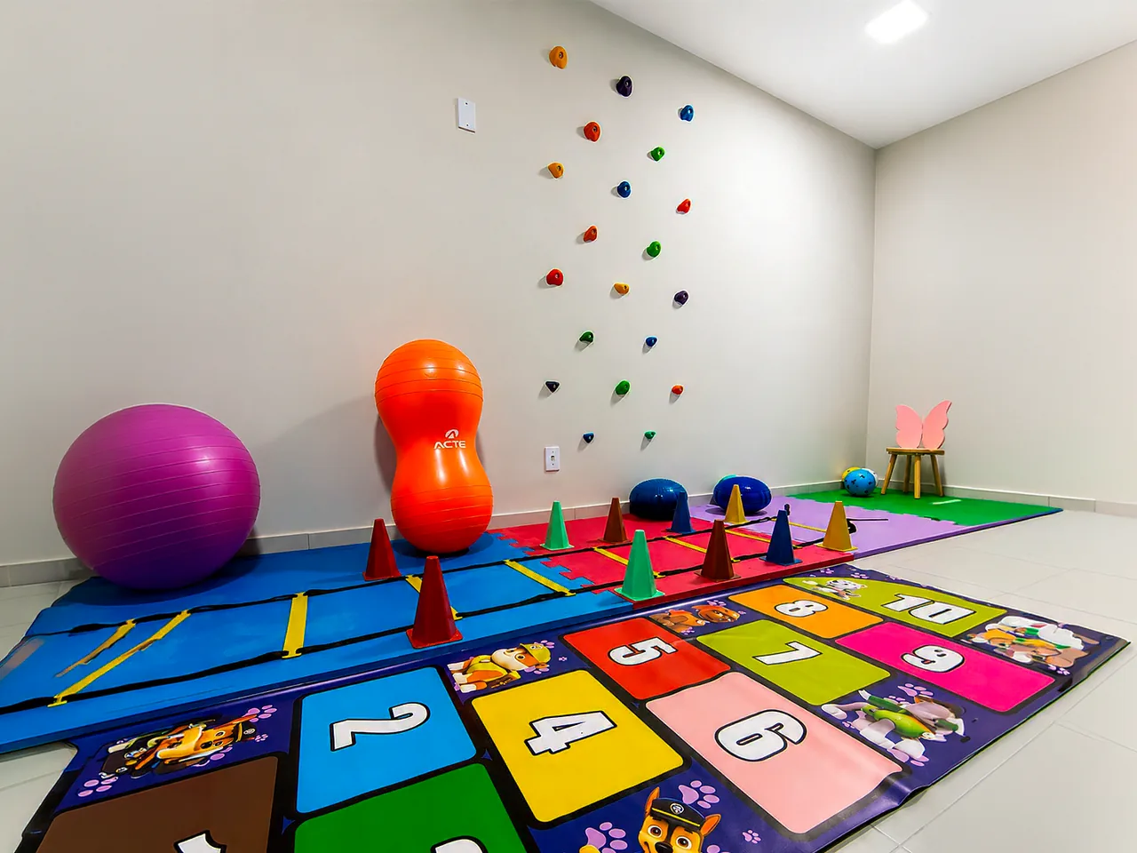 Sala de psicomotricidade com tatame numérico e parede de escalada